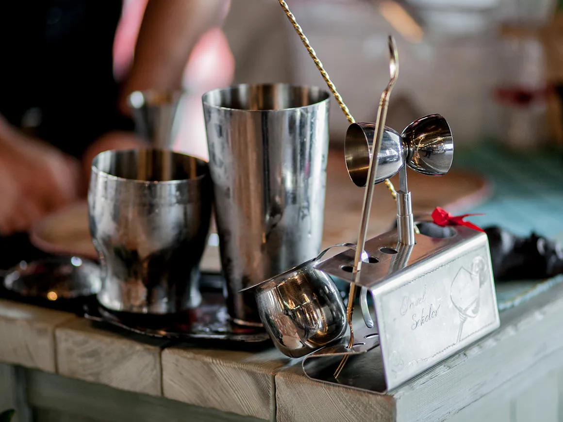 Stainless steel cocktail shakers and jiggers set up on a bar top