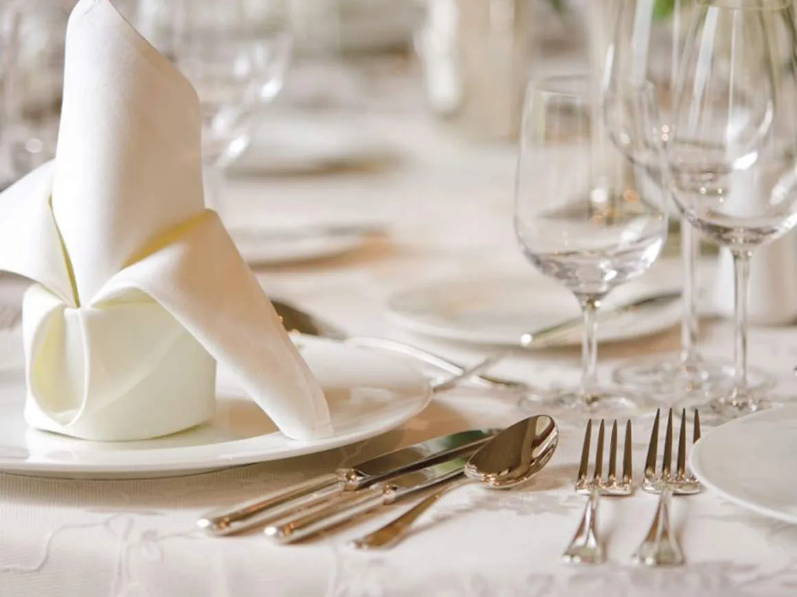 Formal table setting with folded linen napkin, wine glasses, and polished flatware